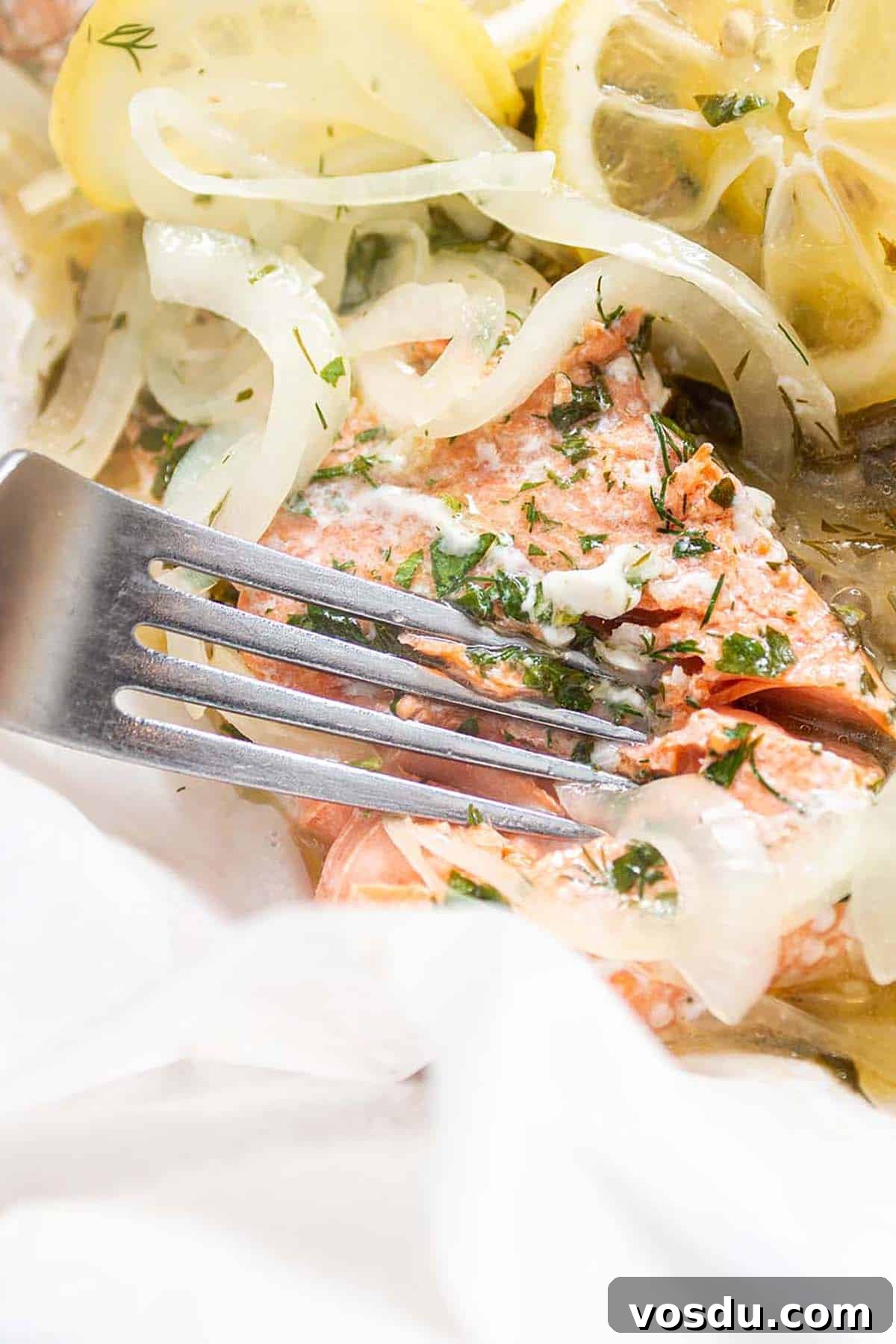 Steamed Salmon with Fresh Herbs and Lemon: Quick Flavorful Recipe 2 a fork cutting into a fresh salmon filet made with lemon and herb and onions.