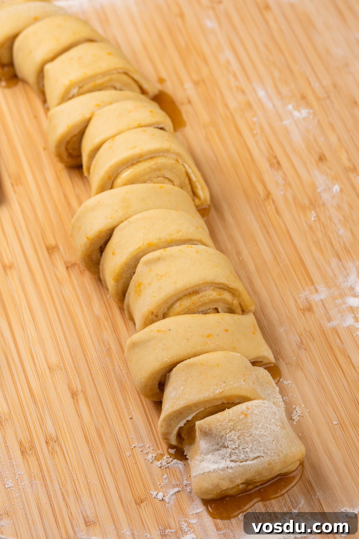 Rolled and sliced orange rolls, ready to be placed in a baking dish.