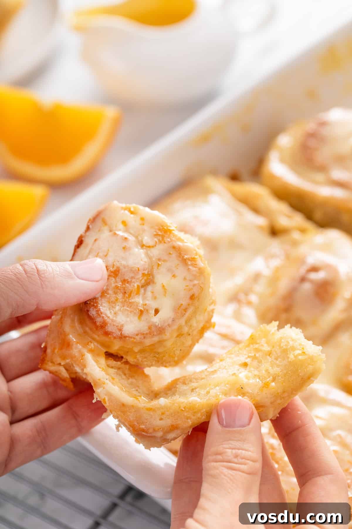 Hands pulling apart a sticky orange roll.