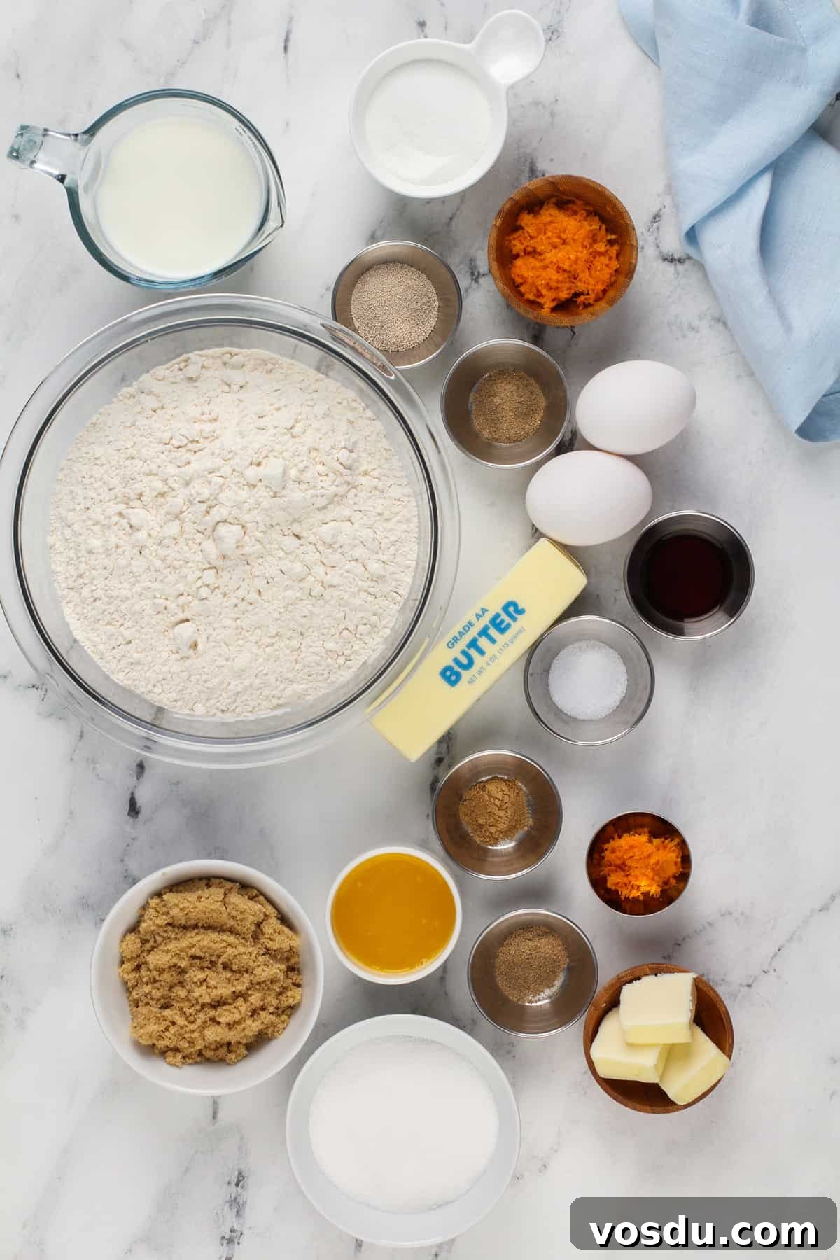 Sticky orange roll ingredients arranged on a marble countertop.