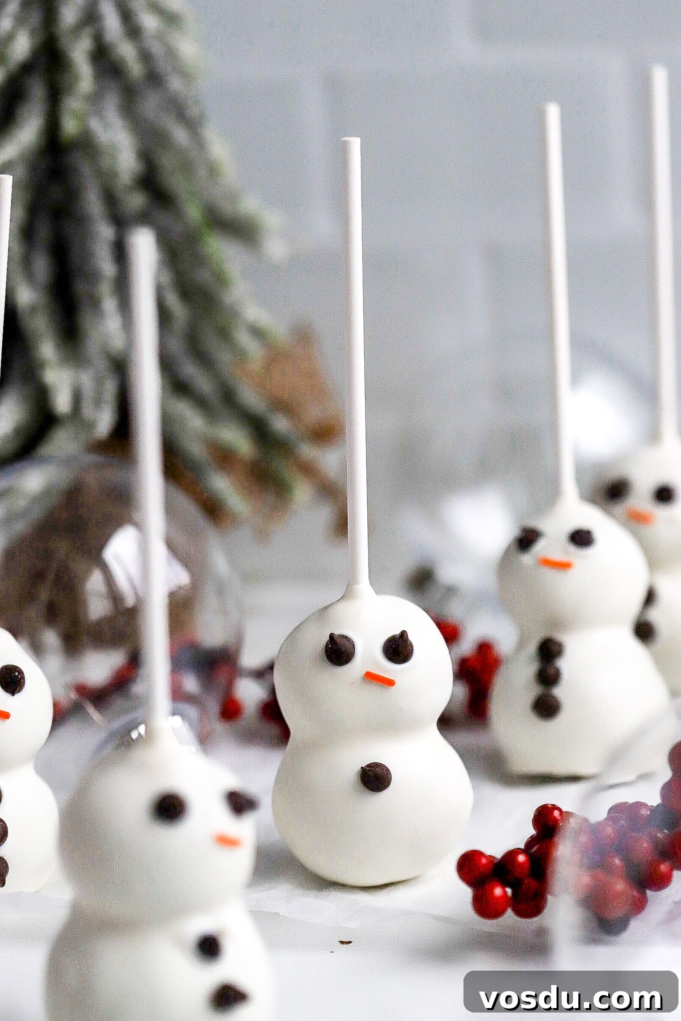 Adorable Snowman Cake Pops Recipe for Christmas Treats 6 easy snowman cake pops on parchment paper with christmas tree in background