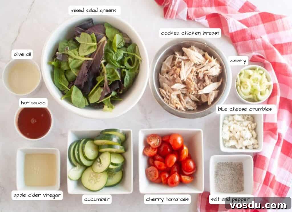 Chef Jenn’s Buffalo Chicken Salad Recipe for Flavorful Lunch 4 Bowls and dishes with mixed salad greens, shredded chicken breast, celery, blue cheese crumbles, cherry tomatoes, cucumber, olive oil, hot sauce, apple cider vinegar, and salt and pepper.