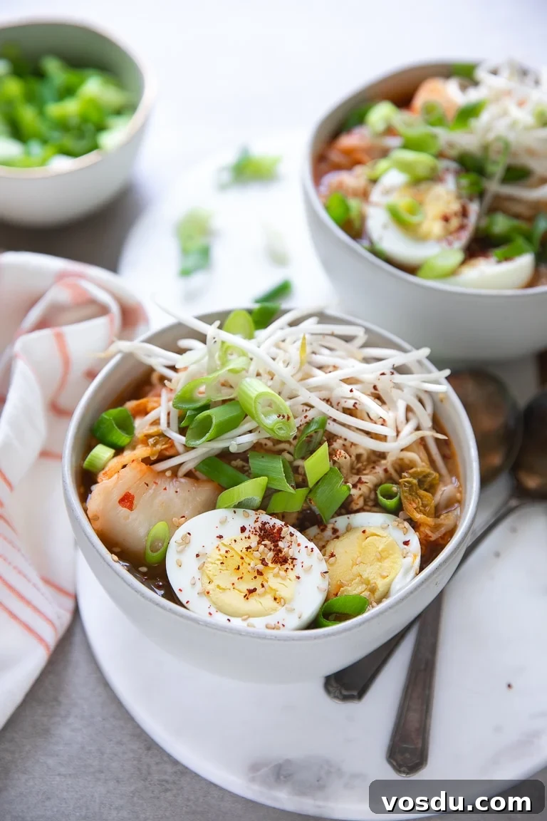 30-Minute Kimchi Ramen Soup Recipe for Flavorful Comfort 3 Two bowls of kimchi noodle soup topped with bean sprouts, scallions, sesame seeds, and halved hard-boiled eggs.