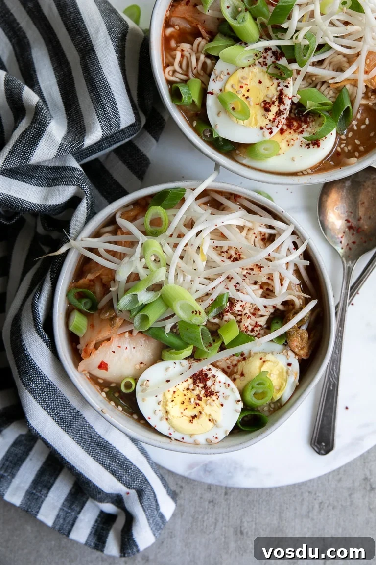 30-Minute Kimchi Ramen Soup Recipe for Flavorful Comfort 4 Two bowls of kimchi noodle soup on a marble board with garnishes.