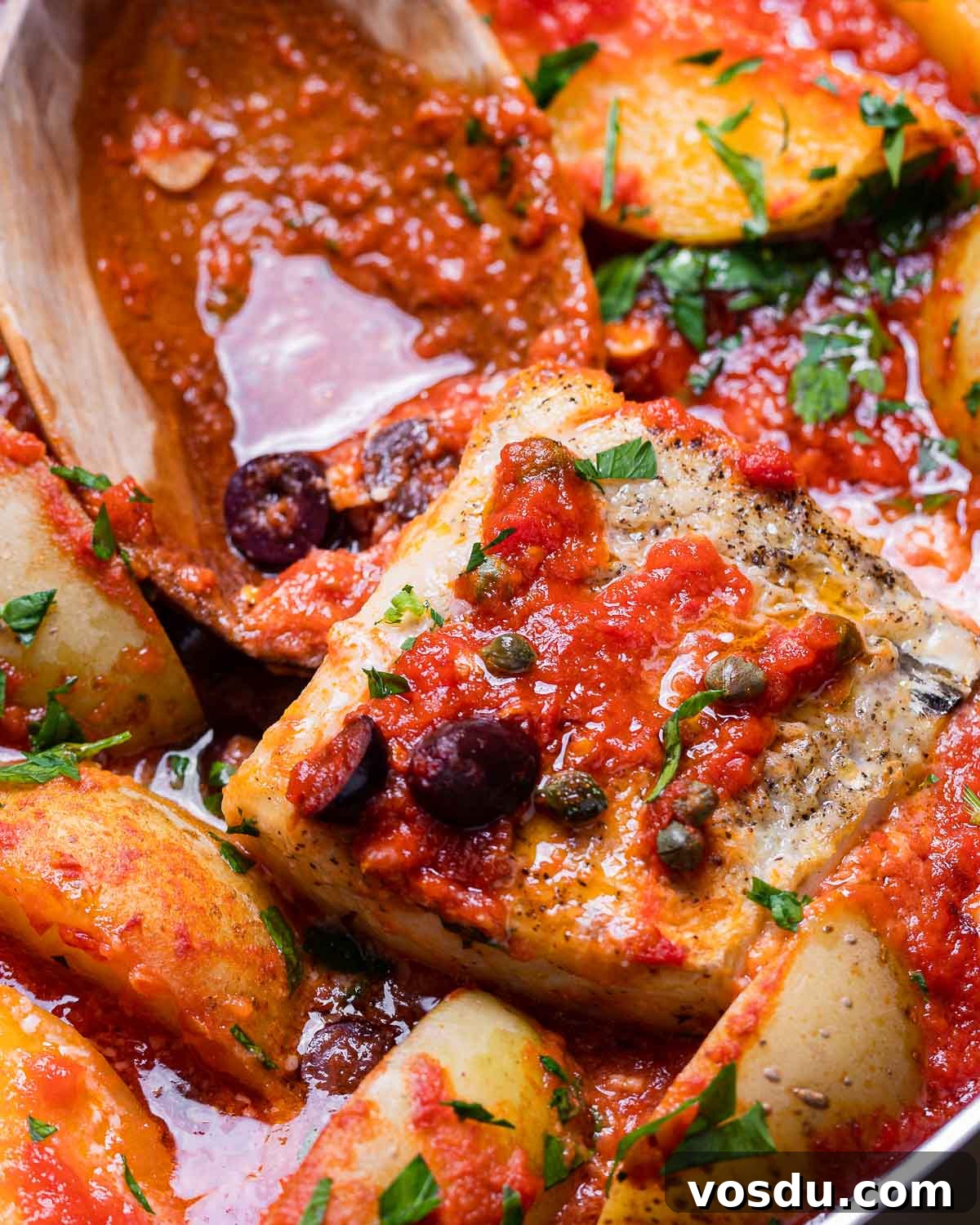 Neapolitan-Style Baccalà: Classic Salted Cod Recipe from Naples 2 Piece of baccala in tomato sauce with large wooden spoon.