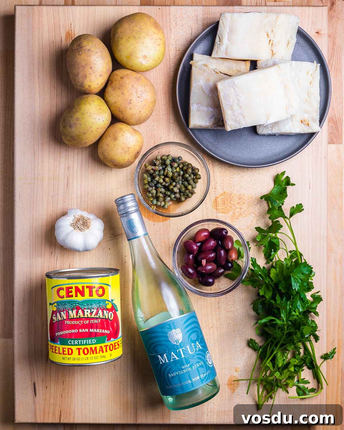 Neapolitan-Style Baccalà: Classic Salted Cod Recipe from Naples 3 Ingredients shown: potatoes, baccala, capers, garlic, tomatoes, white wine, olives, and parsley.