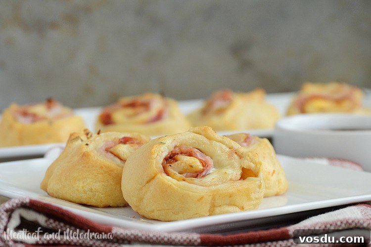 Ham and Cheese Crescent Roll-Ups Baked to Golden Perfection 9 baked ham and cheese roll ups with barbecue sauce on plate