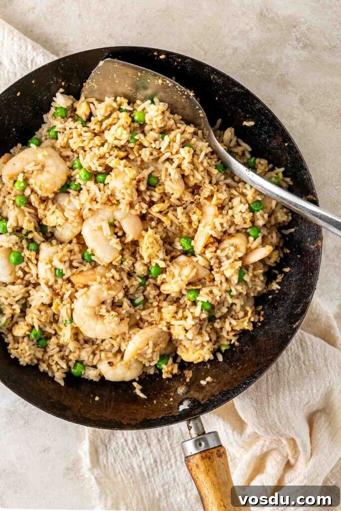 Prawn and Egg Fried Rice Recipe — Quick Weeknight Meal 9 Prawn and egg fried rice with peas in a wok.