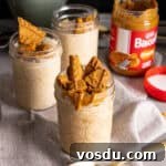 Several mason jars with biscoff overnight oats on a gray table.