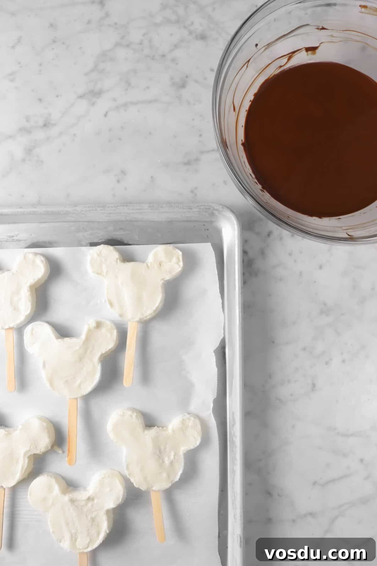 Mickey Mouse Ice Cream Bars: Where to Buy & Nutrition Facts 13 mickey ice cream bars on sheet pan with bowl of chocolate