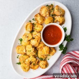 Crispy Air-Fried Tortellini with Garlic Parmesan Dipping Sauce 10 a white platter of breaded air fryer tortellini with marinara saucer on the side