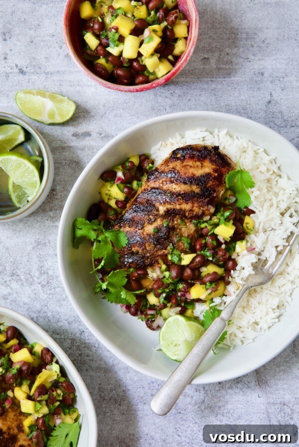 Caribbean Chicken with Black Bean and Mango Salsa Recipe 13 Caribbean Jerk Chicken with Mango Black Bean Salsa in white bowl garnished with cilantro and squeezed lime wedges.