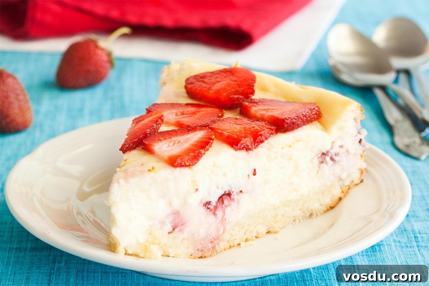 Slice of strawberry shortcake cheesecake on white plate
