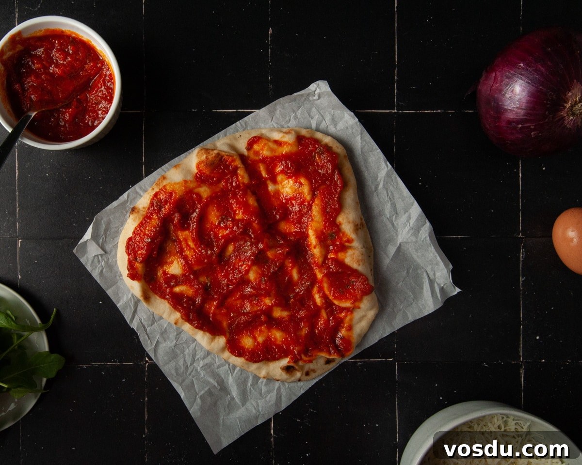 15-Minute Vegetarian Naan Breakfast Pizza Recipe 4 Adding tomato sauce to naan bread.