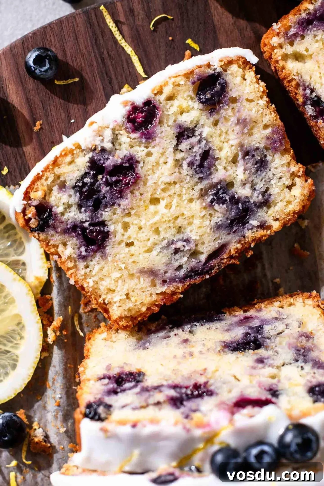 Lemon Blueberry Loaf Cake Recipe for Moist, Zesty Slices 11 sliced lemon blueberry quick bread on parchment lined wooden serving board-3