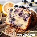 sliced lemon blueberry quick bread on parchment lined wooden serving board