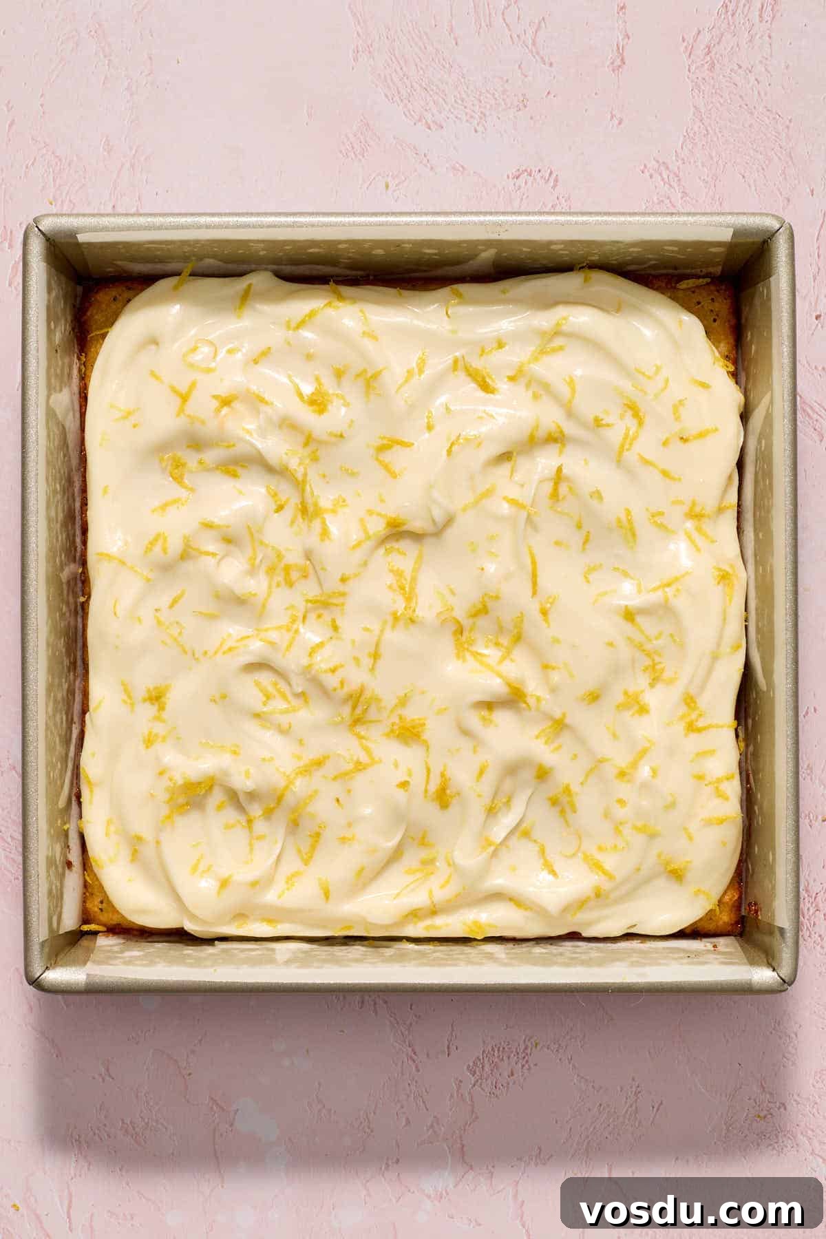 Almond Flour Lemon Poppy Seed Cake Recipe for Moist, Zesty Loaf 12 Frosting spread over cake with lemon zest sprinkled on top.