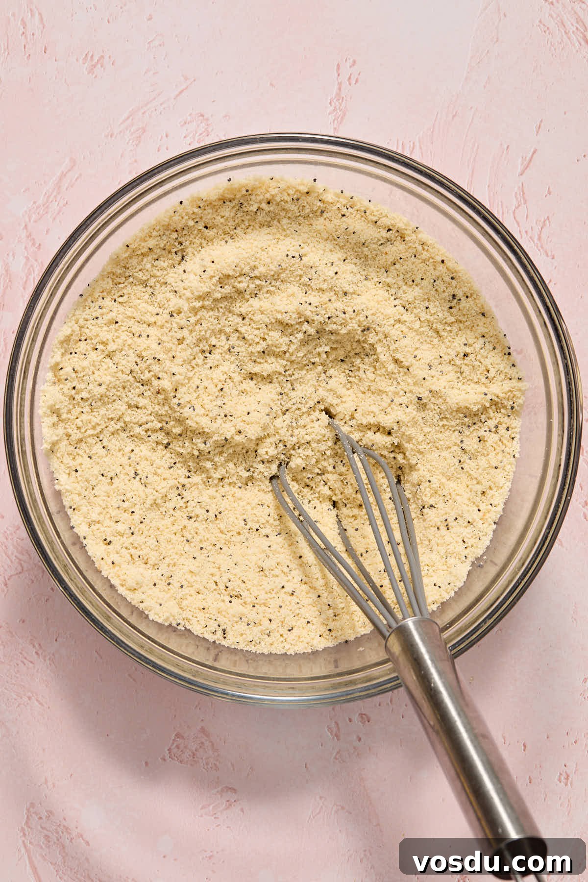 Almond Flour Lemon Poppy Seed Cake Recipe for Moist, Zesty Loaf 5 Dry ingredients, including poppy seeds, whisked together in a bowl.