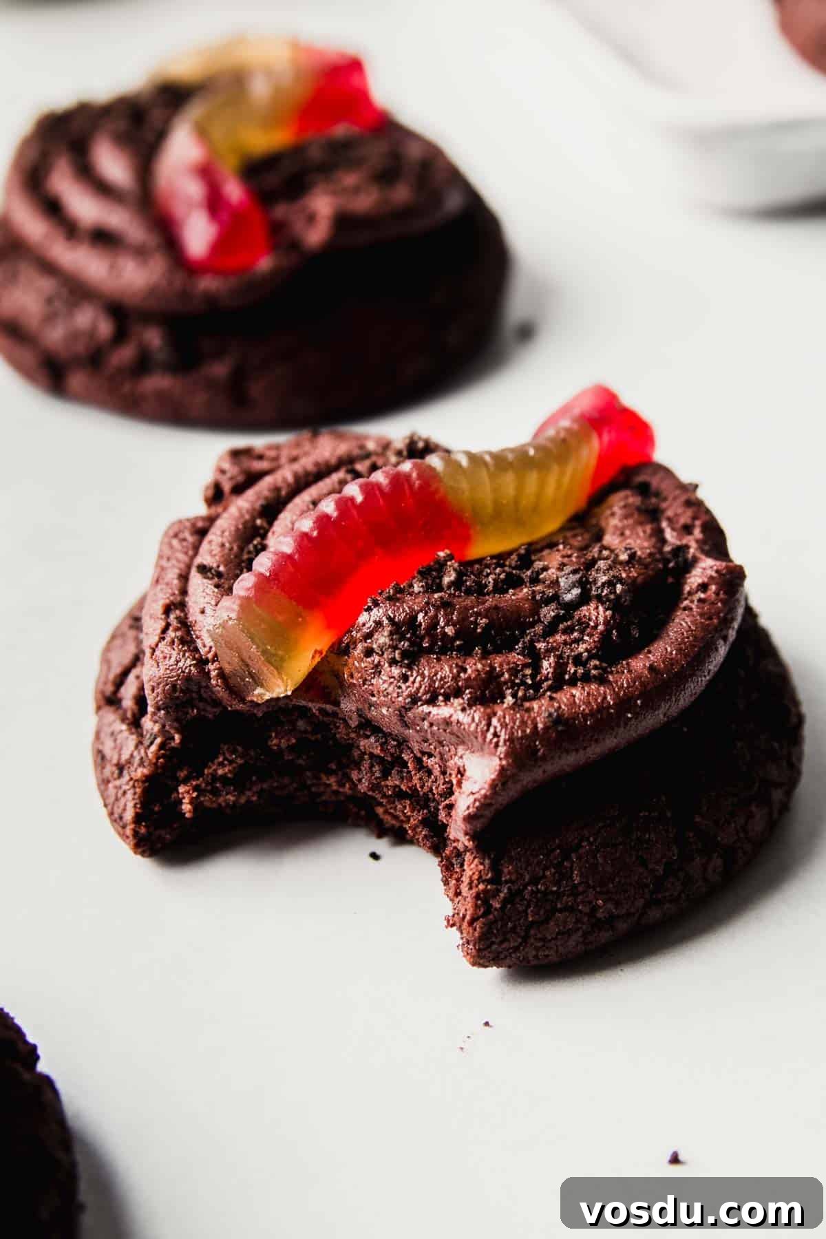 Gluten-Free Crumbl Oreo Dirt Cookies Copycat Recipe 8 Chocolate cookie with buttercream icing, Oreo cookie crumbles, and gummy worm on top with bite taken.