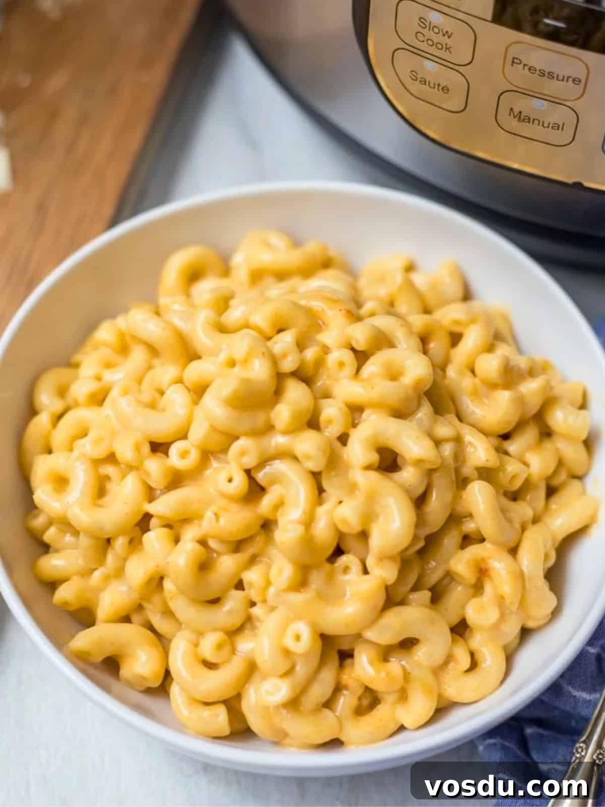 Instant Pot Mac and Cheese Bowl of cheesy, creamy Instant Pot Macaroni and cheese next to pressure cooker.