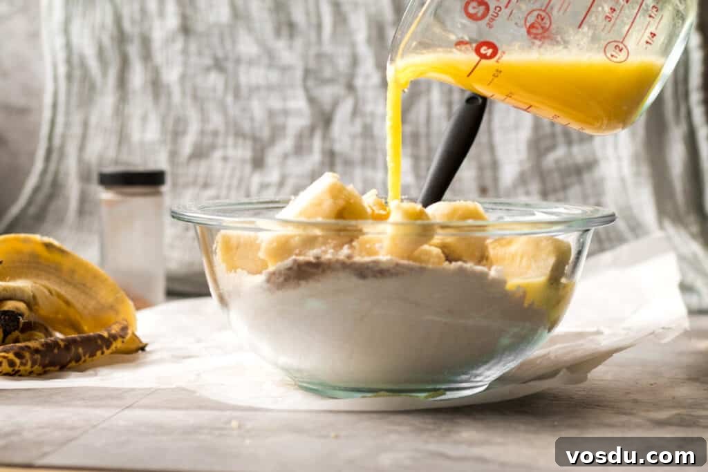One-Bowl Chocolate Chip Banana Bread Recipe 5 pouring liquid ingredients into a glass bowl