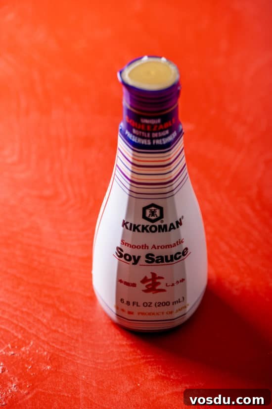 10 Essential Pantry Ingredients Every Home Cook Needs 5 Jar of Kikkoman Soy Sauce on red table.