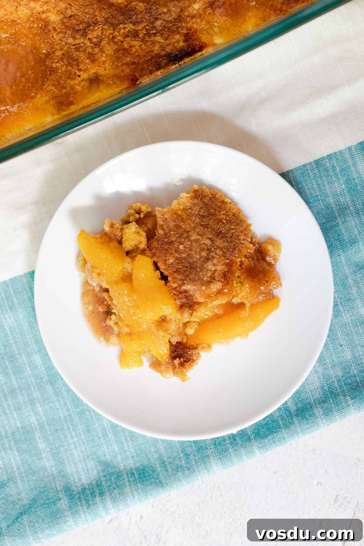 Quick Peach Cobbler Made with Cake Mix and Canned Peaches 9 A serving of peach cobbler on a small plate.
