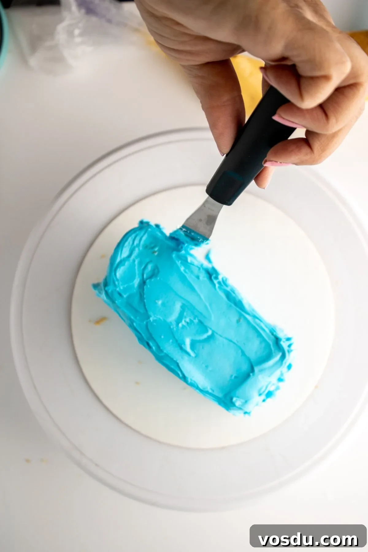 Bluey Cake Recipe with Simple Step-by-Step Tutorial 12 Sky blue frosting on a piece of cake being smoothed.