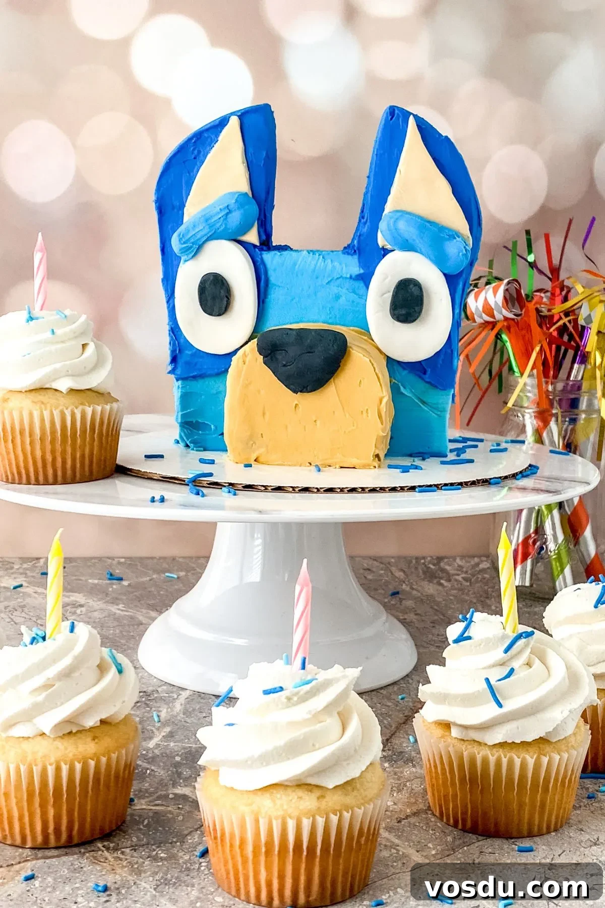 Bluey Cake Recipe with Simple Step-by-Step Tutorial 4 Cupcakes sitting in front of a Bluey Cake.