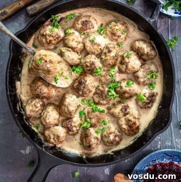 An overhead photo of cast-iron skillet with Swedish meatballs in a creamy gravy.