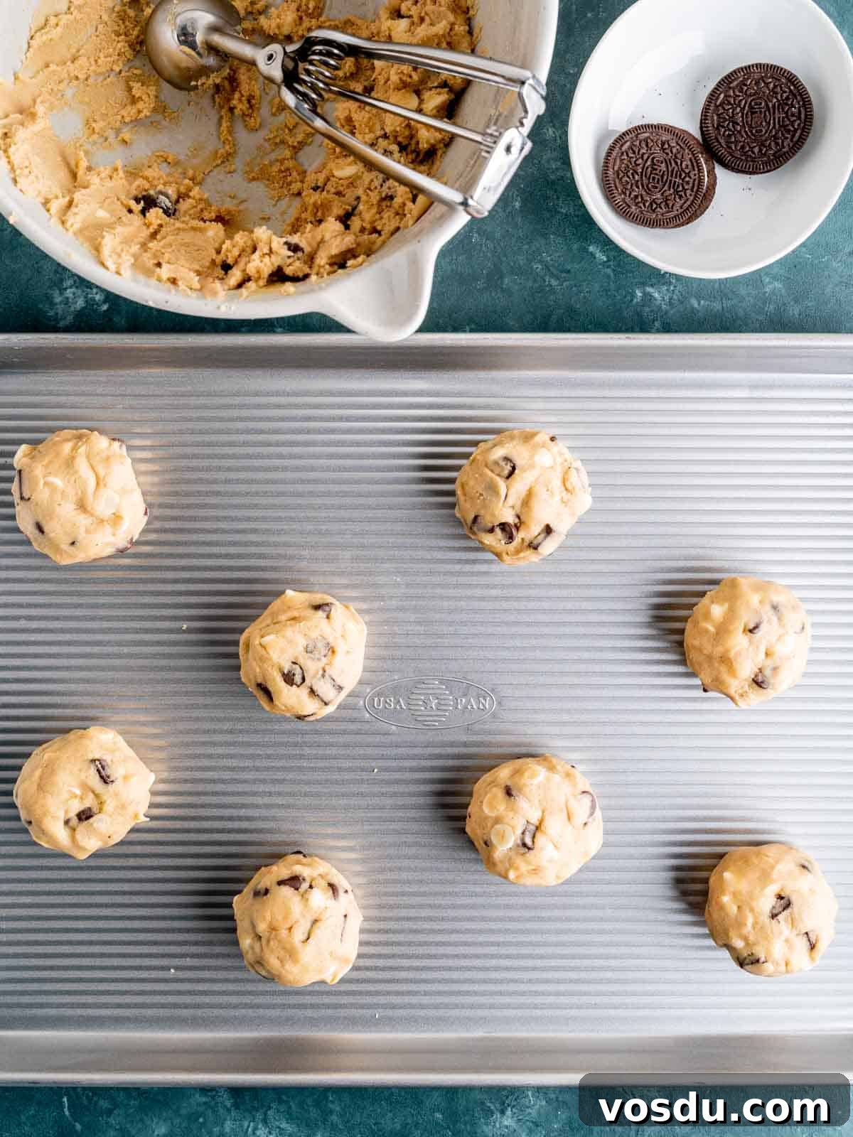 Oreo stuffed chocolate chip cookie dough balls on a baking sheet.
