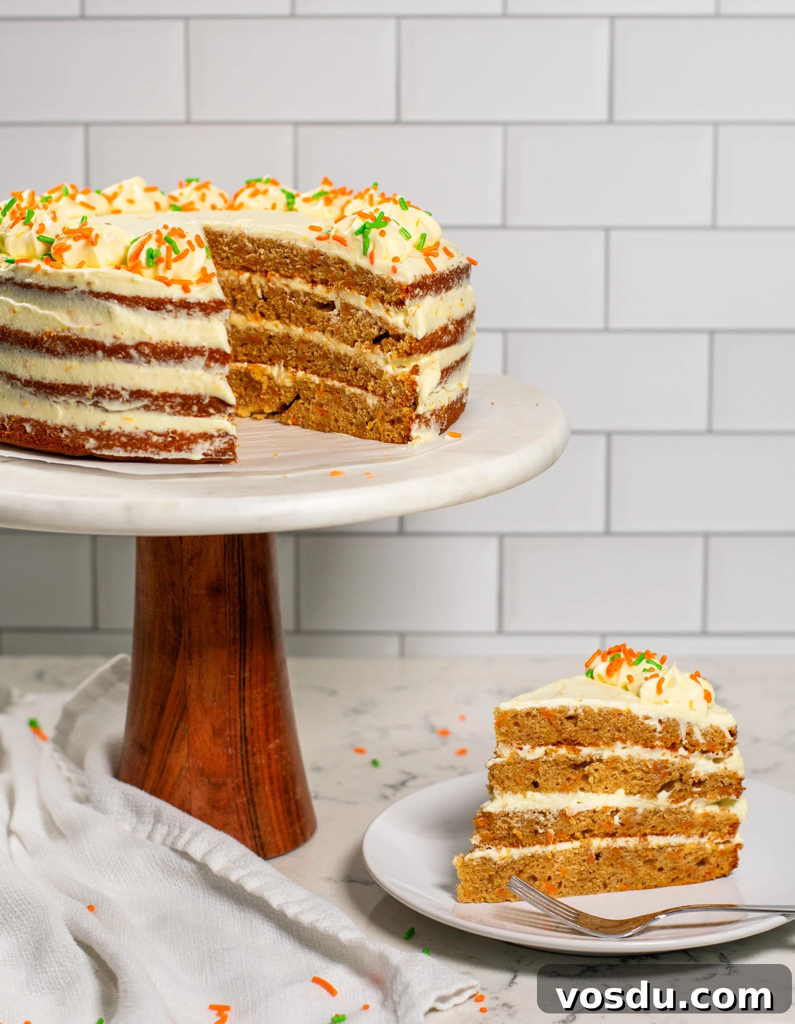 Classic Danish Carrot Cake Recipe with Cream Cheese Frosting 2 A carrot cake on a cake stand with a piece cut out of it.