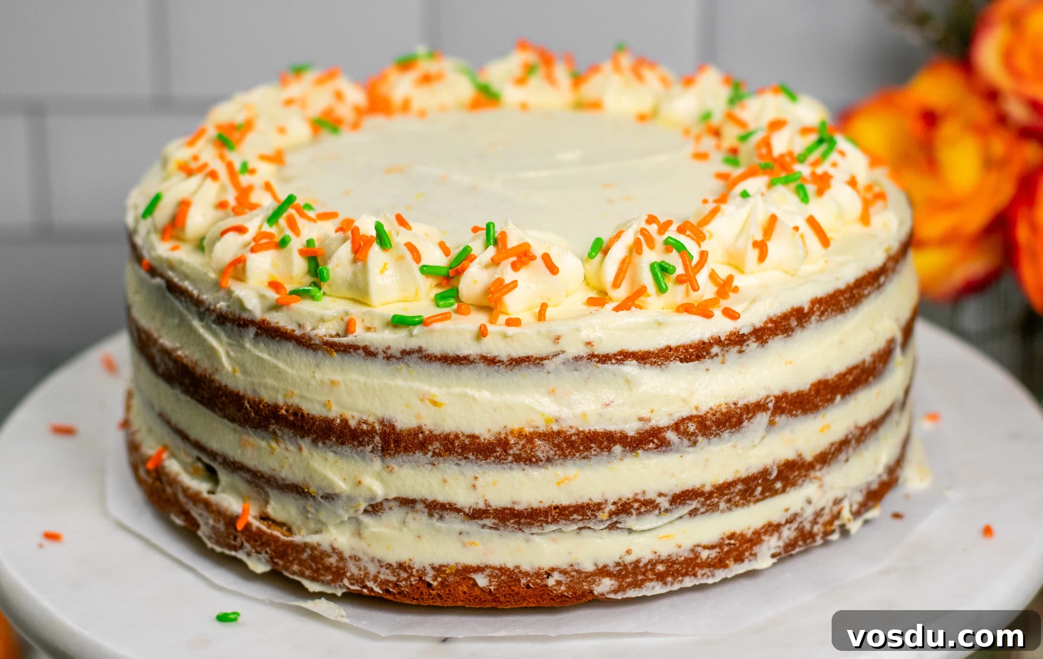 A carrot cake with cream cheese icing on a cake stand.