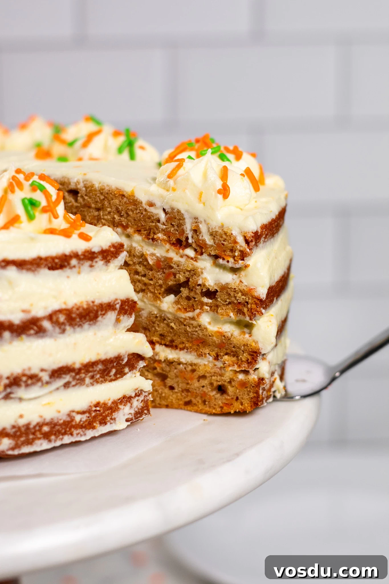 Classic Danish Carrot Cake Recipe with Cream Cheese Frosting 9 A slice of carrot cake being cut out of the larger cake.