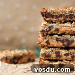 stack of magic cookie bars with beige spotted background and coconut flakes