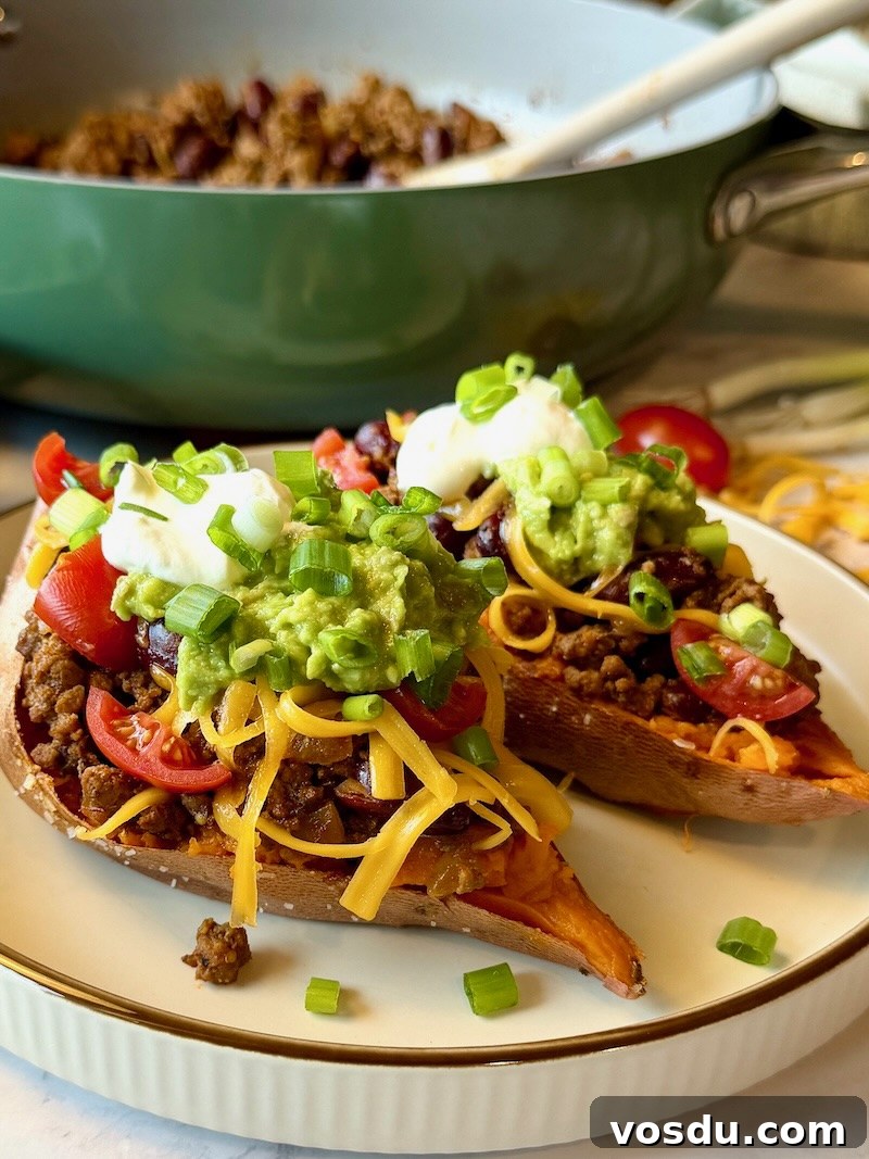 Taco-Stuffed Baked Sweet Potatoes — Savory Comfort Meal 10 Halved sweet potatoes layered with meat filling, cheese, tomatoes, smashed avocado, sour cream, and green onions.