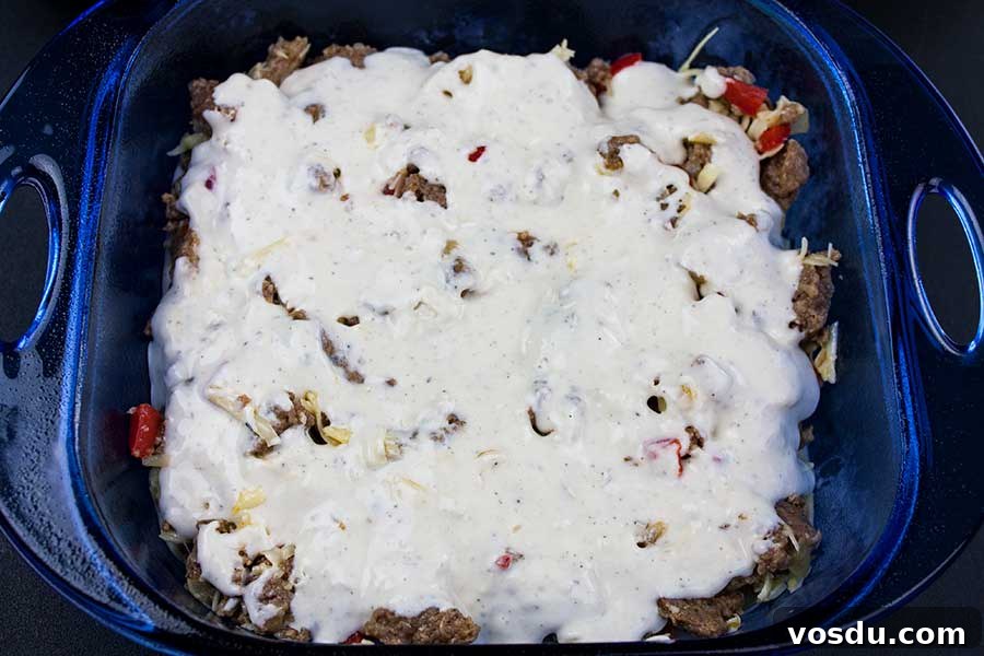 Savory Sausage Breakfast Cake Recipe for Brunch and Meal Prep 4 Sausage Breakfast Cake Recipe - uncooked batter and sausage layered in blue glass baking pan