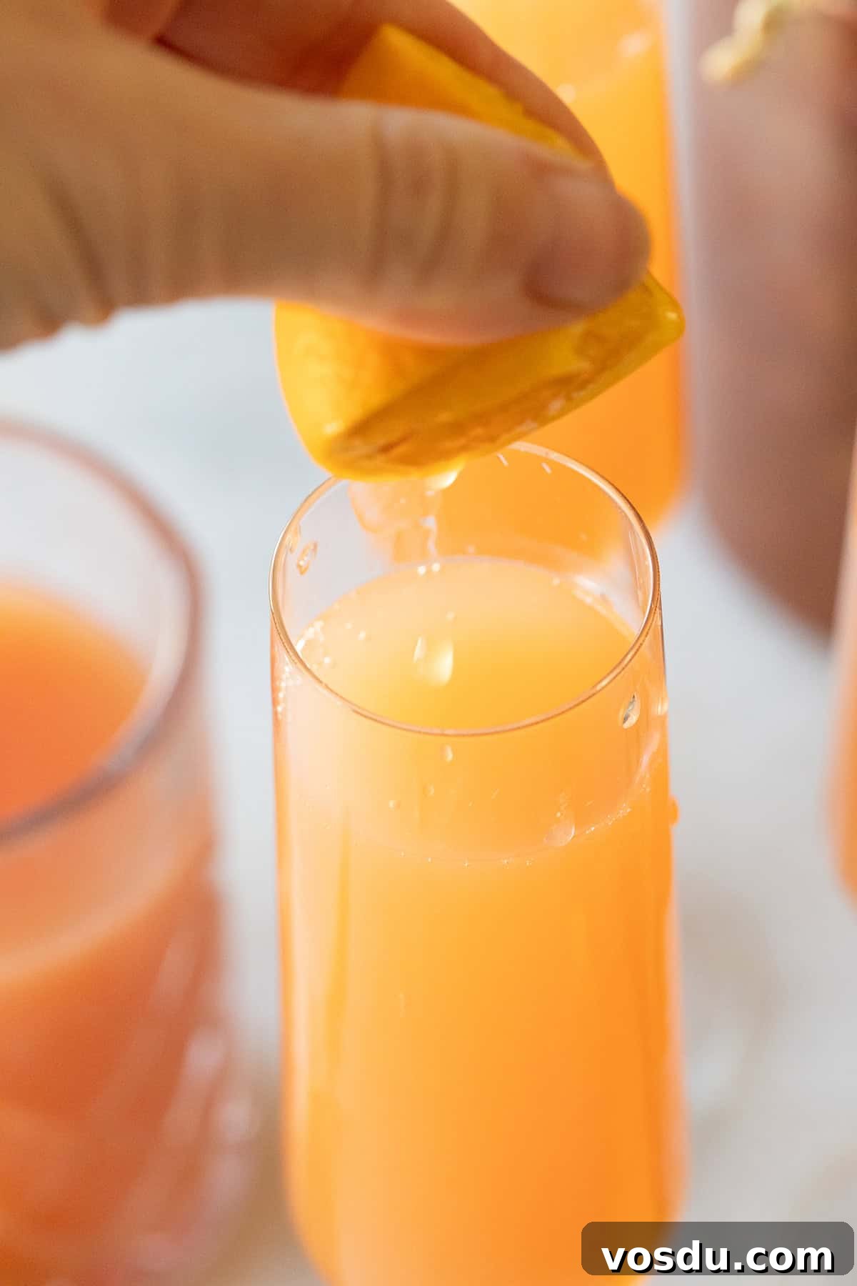 Citrus Grapefruit Mimosa Recipe — Bright Brunch Cocktail 6 Squeezing orange juice into a glass.