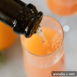 Pouring Champagne into a Champagne glass to make a grapefruit mimosa.
