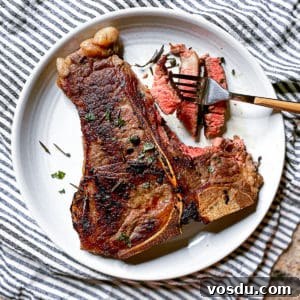 fork stabbing sous vide porterhouse steak with plate on a tablecloth
