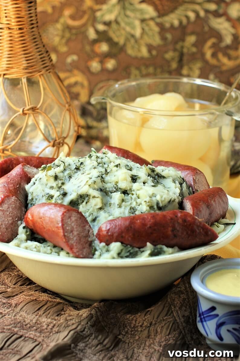 Dutch Kale Stamppot with Sausage — Classic Dutch Comfort Meal 4 bowl of boerenkool with sausages, bowl of pears, mustard pot, dark fabric background