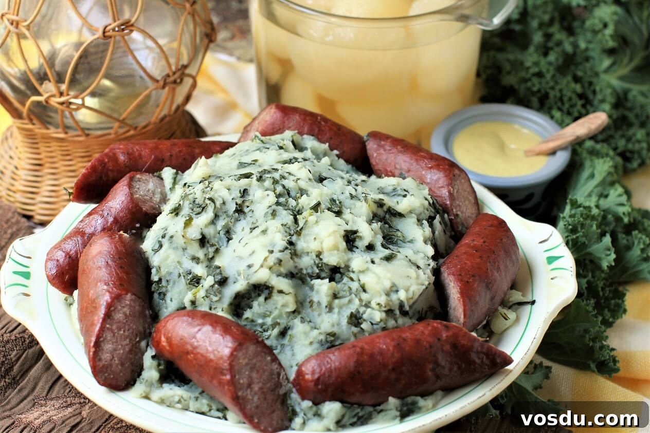 Dutch Kale Stamppot with Sausage — Classic Dutch Comfort Meal 9 a platter loaded with kale mashed potatoes surrounded by chunks of cooked smoked sausage, bowl of canned pears and mustard dish behind