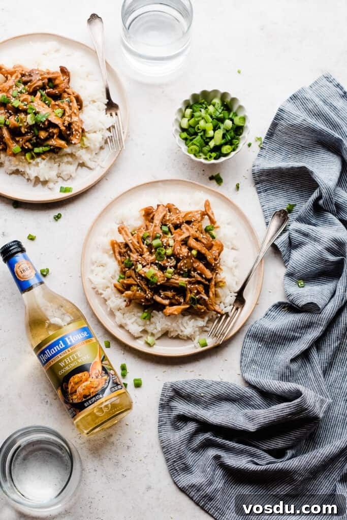Slow Cooker Honey Garlic Chicken Recipe for Tender, Flavorful Meat 3 Two plates of honey garlic chicken atop rice, with a bottle of white cooking wine laying next to them.