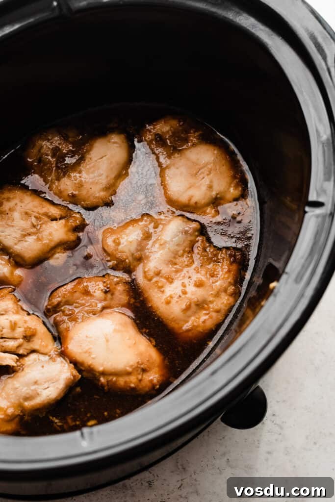 Slow Cooker Honey Garlic Chicken Recipe for Tender, Flavorful Meat 5 Cooked chicken thighs in sauce in the crock pot.