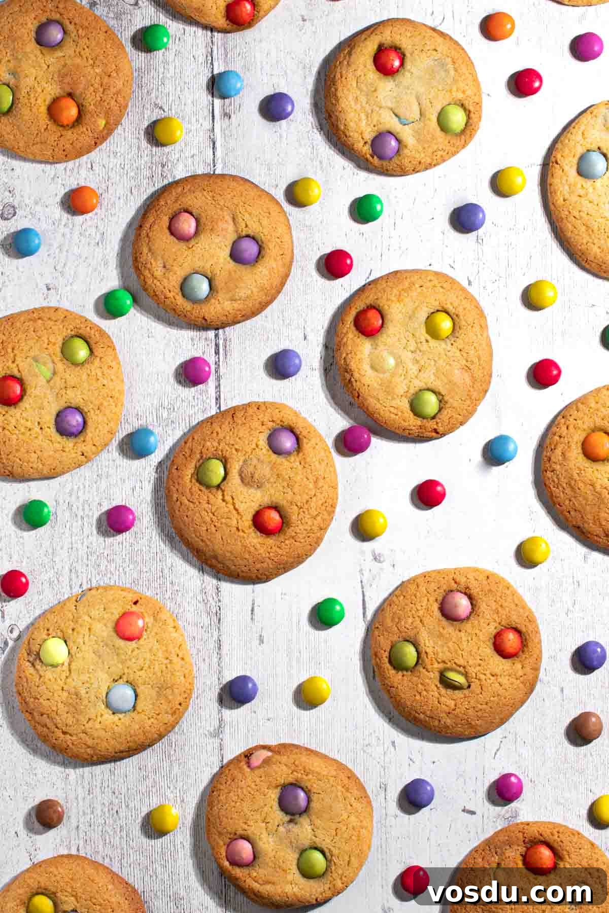 Cheerful Smartie Cookies Recipe for Colorful Party Treats 2 Smartie cookies on a white background with scattered Smarties between the cookies.