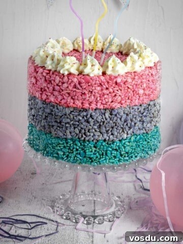 A three layered Rice Krispie cake on a cake stand, surrounded by balloons.