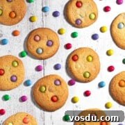 Cheerful Smartie Cookies Recipe for Colorful Party Treats 8 Smartie cookies on a white background with scattered Smarties between the cookies.