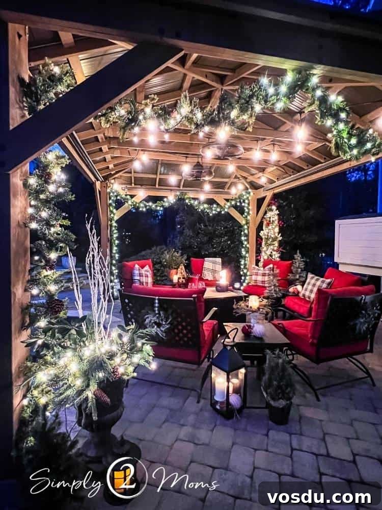 Country Chic Christmas Home Tour That Inspires Holiday Decorating 24 Paver patio with large gazebo decorated for Christmas with lighted garland and string lights. Iron furniture with red cushions sit around a coffee table with a small firepit on top.