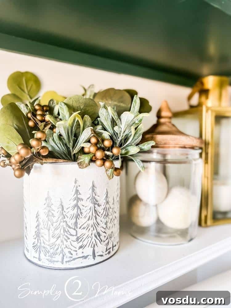 Country Chic Christmas Home Tour That Inspires Holiday Decorating 28 Shelf in a laundry room above the washer and dryer with a cream painted bucket with Christmas trees on it is filled with greenery and gold berries. A cannister with a wood lid holds dryer balls.