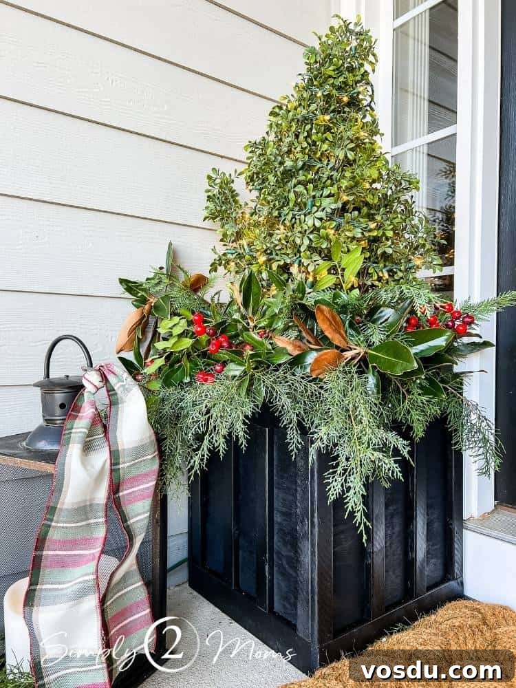 Country Chic Christmas Home Tour That Inspires Holiday Decorating 5 DIY board and batten planter box painted black holding a faux boxwood topiary with Christmas lights. The bottom of the tree is surrounded by assorted fresh greenery for a winter planter with red berries.